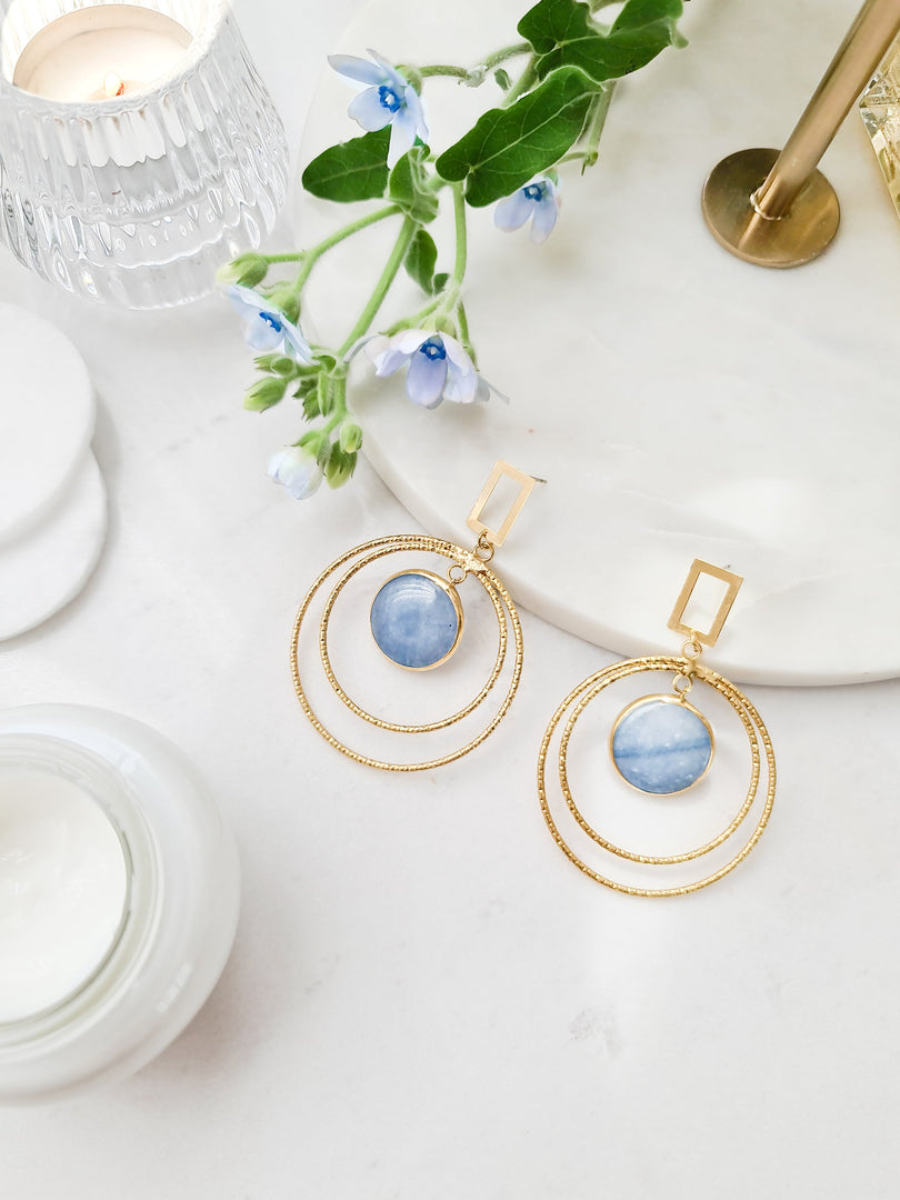 Turquoise circle earrings with gold-plated design on marble surface.